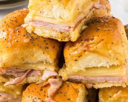 Ham and cheese sliders stacked on a plate.