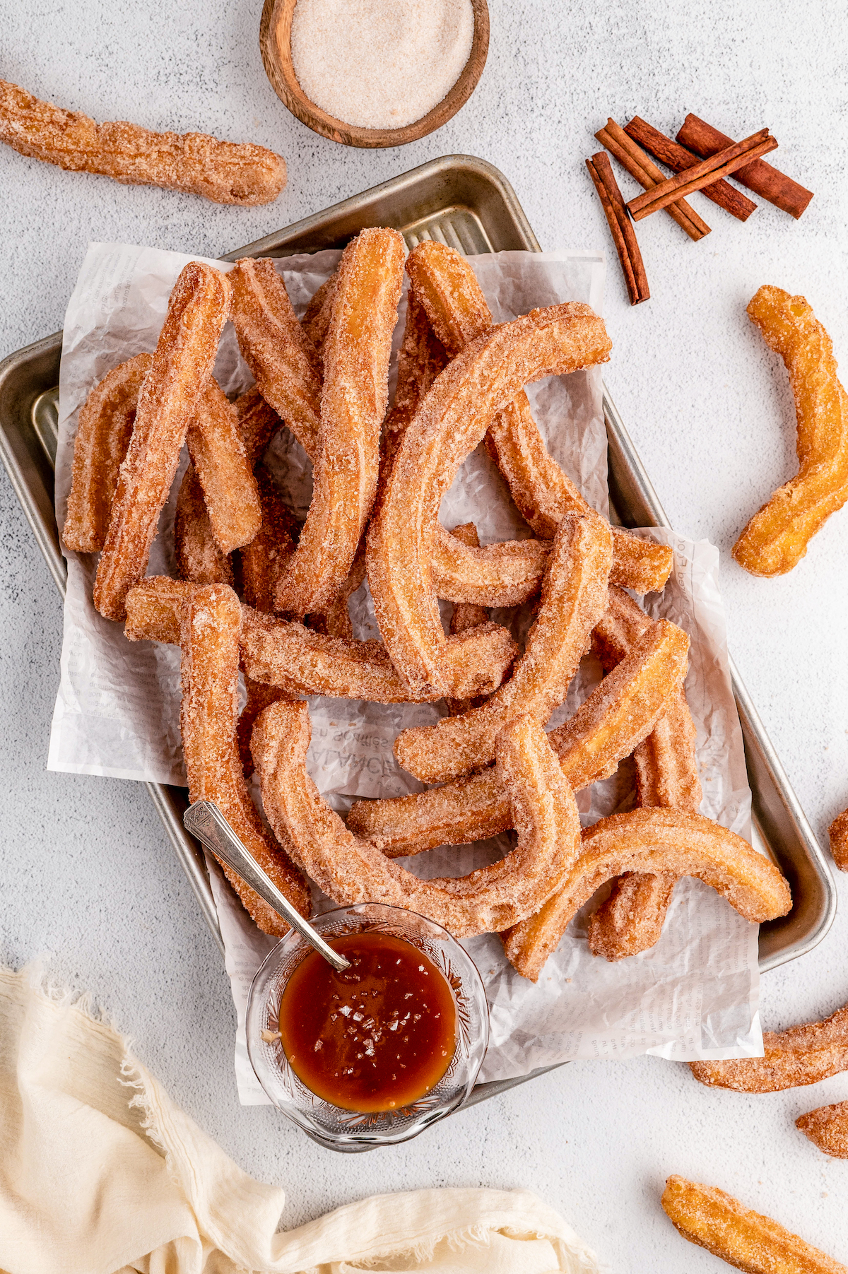 Baking tray with homemade churros and caramel sauce on the side.