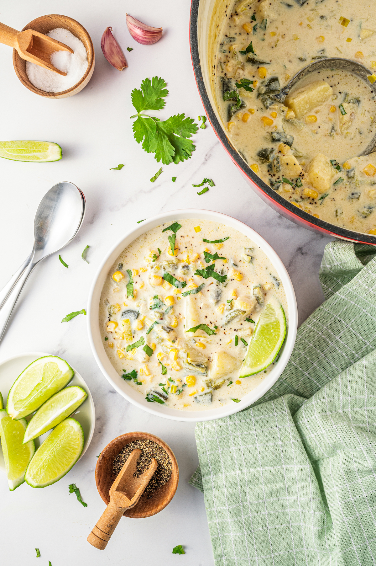 Pot next to a bowl of poblano corn soup.