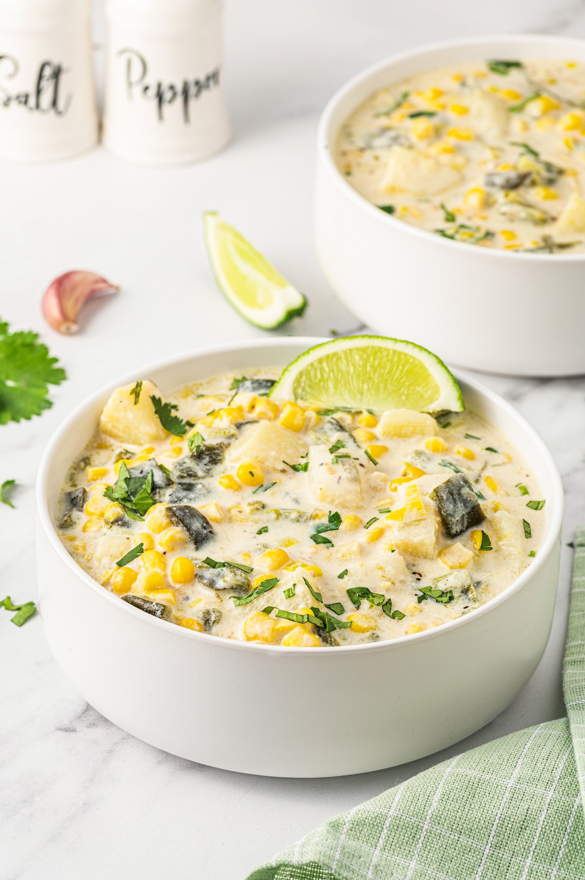 Bowl of poblano corn soup with a lime wedge.