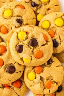 Reese's Pieces cookies piled on top of each other on a plate.