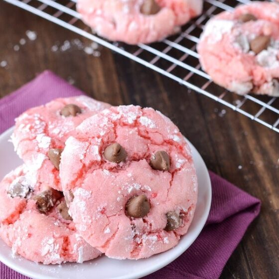 Strawberry Chocolate Chip Cookies on a white plate with remaining cookies on a rack