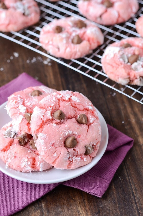 Strawberry Chocolate Chip Cookies on a white plate with remaining cookies on a rack