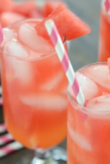 Glasses of Watermelon Lemonade rimmed with a piece of Watermelon with pink and white straws