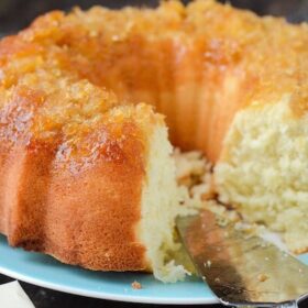 A Pineapple Coconut Bundt Cake on a blue plate with a slice missing