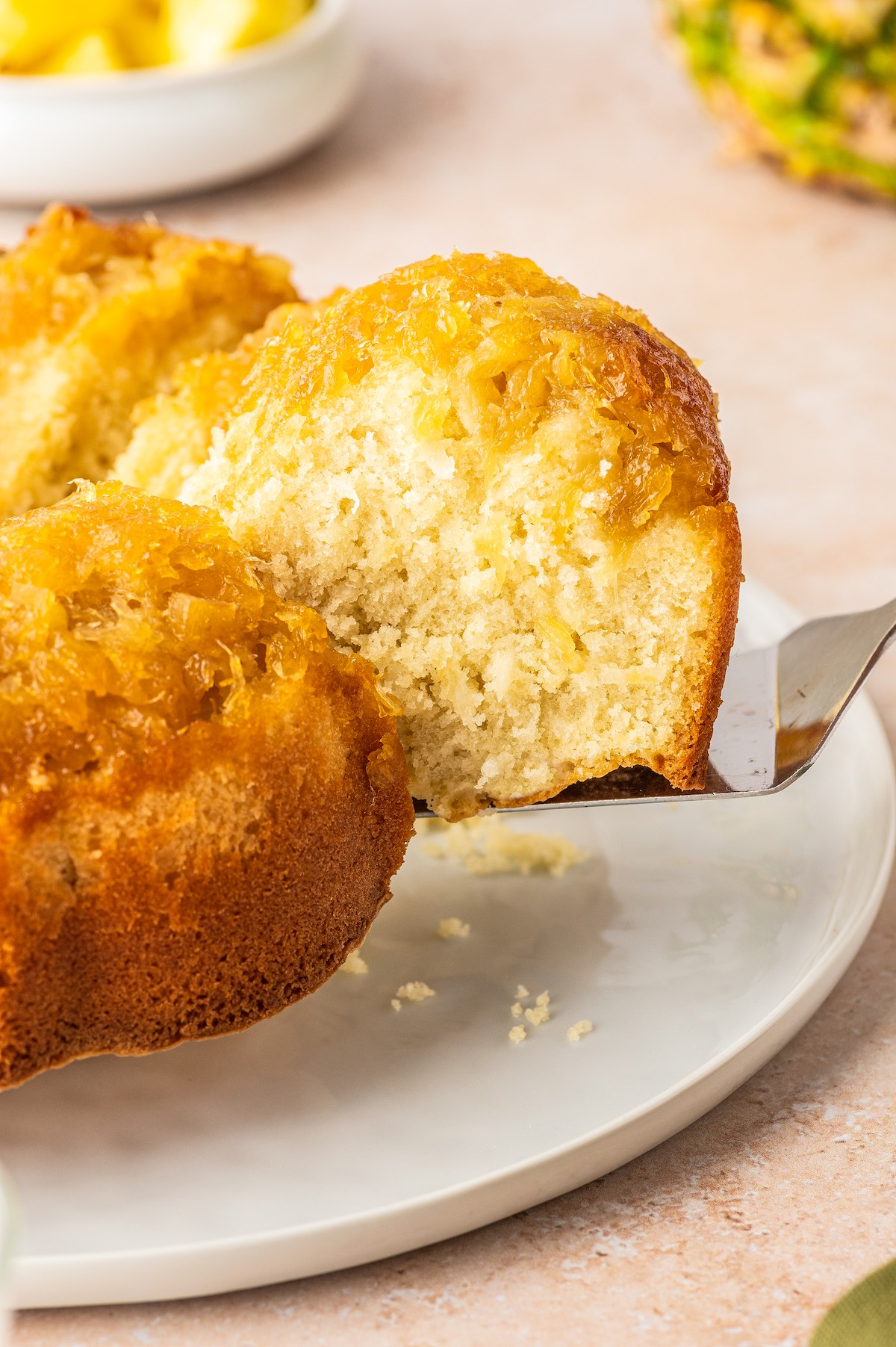 Lifting a slice of pineapple coconut bundt cake with a cake server.