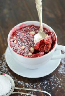 Red Velvet mug cake in a white coffee mug with a spoon.