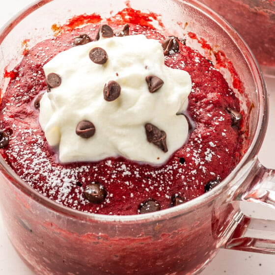 A clear glass mug with a single-serve red velvet cake baked in it.