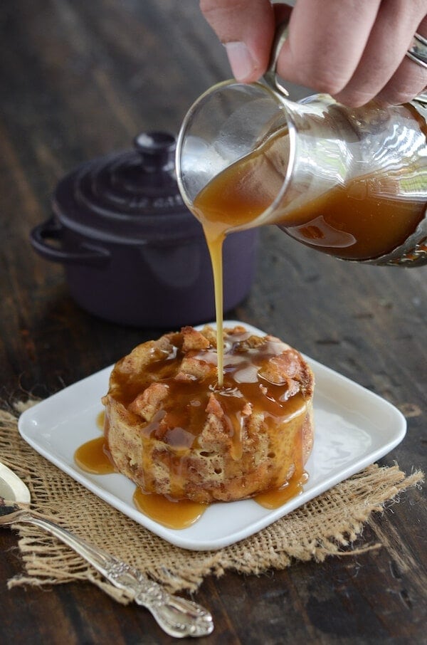 Donut Bread Pudding on a plate with rum sauce being poured on top. 