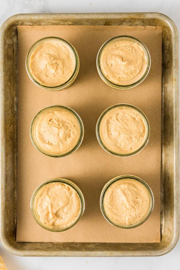 Overhead shot of mini mason jars filled with cheesecake mixture.