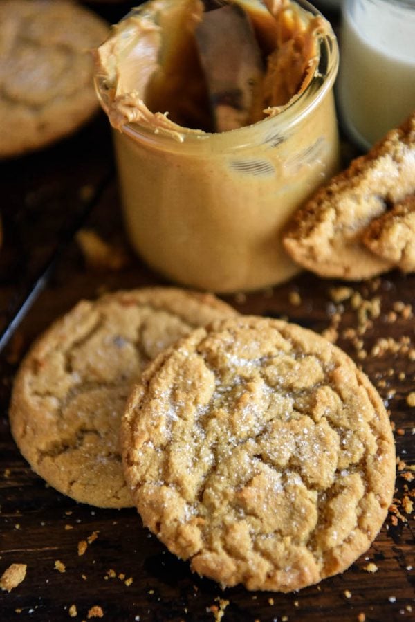 Close up of two Peanut Butter Cookies stacked on top of each other with a peanut butter jar behind them