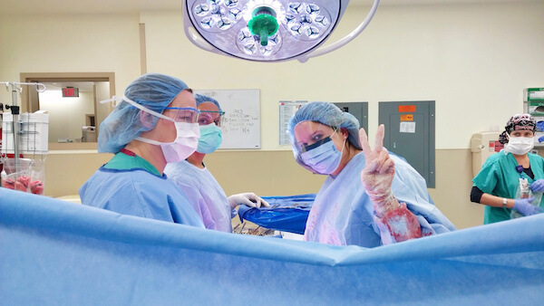 Doctors and Nurses Preparing for Birth with One Giving a Peace Sign to the Camera