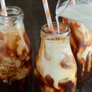 Thai Iced Tea with cream being poured in glass and pink and white straws