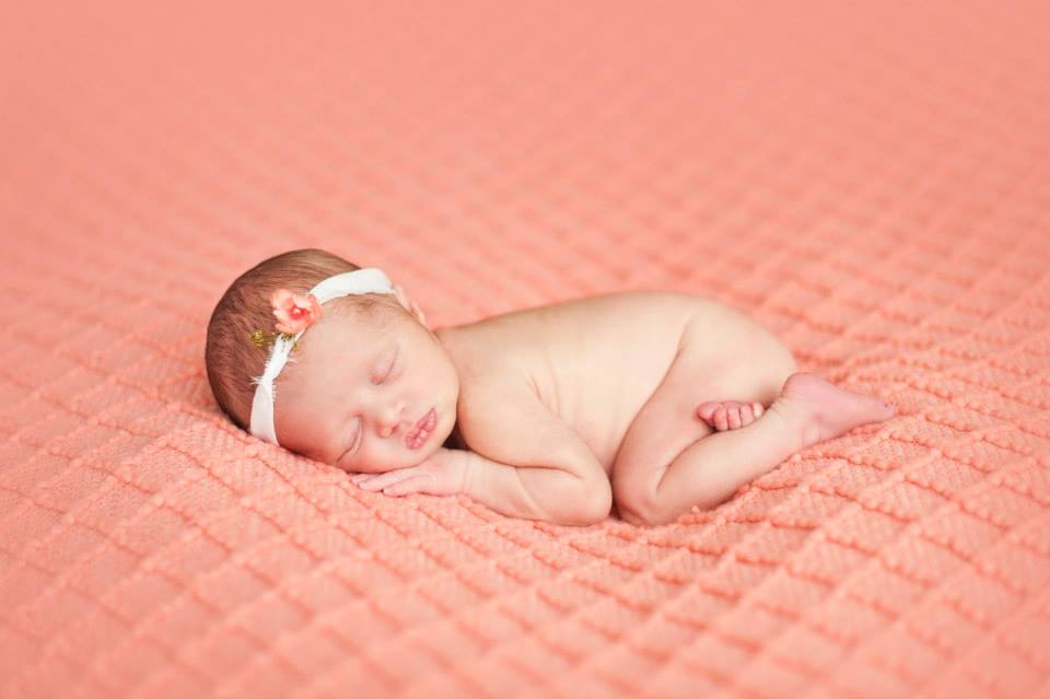 A Newborn Baby Girl Sleeping on a Salmon-Colored Blanket