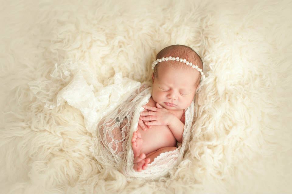 A Newborn Baby Resting on Top of a Fluffy White Surface