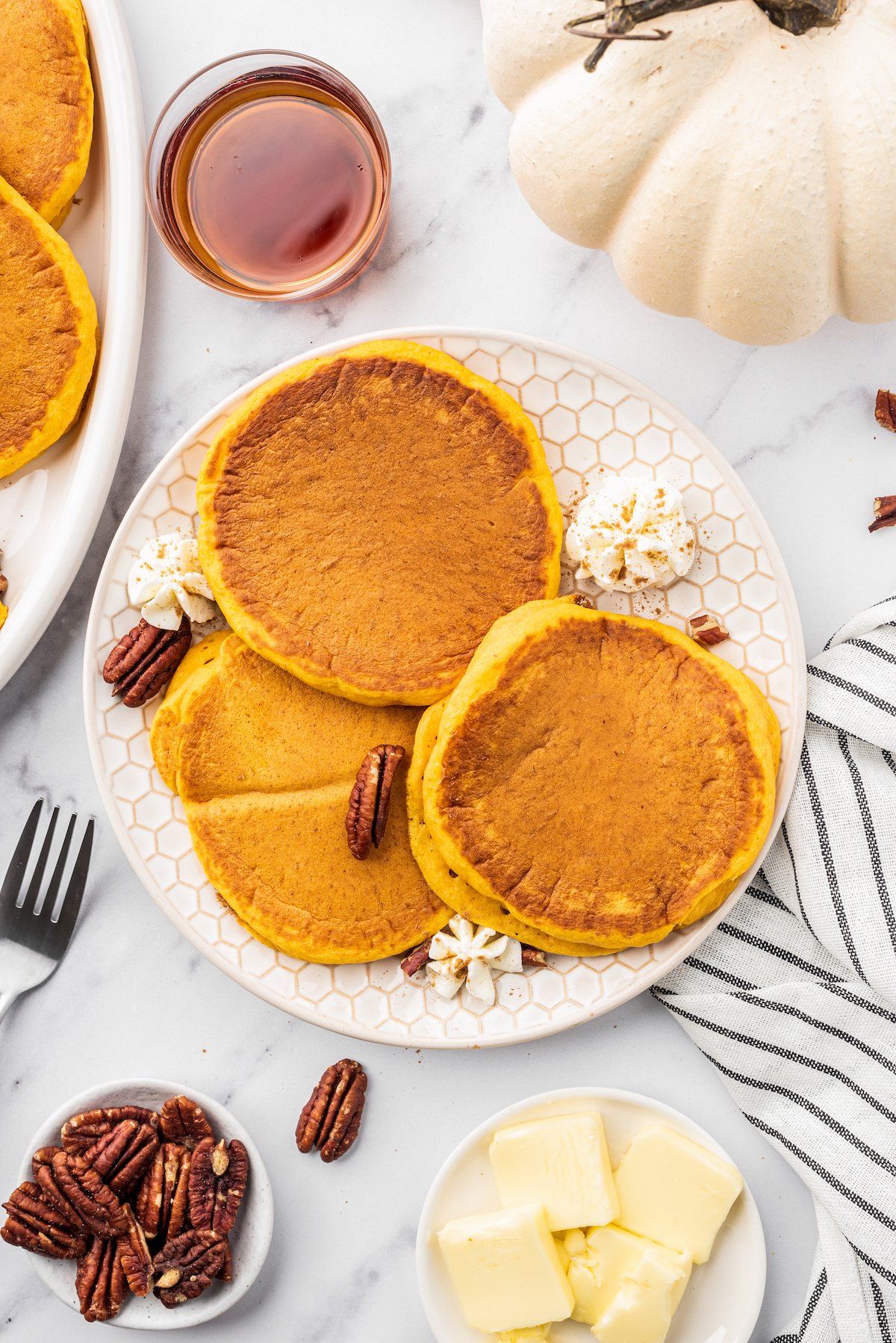 a plate of pumpkin flavored pancakes garnished with pecans