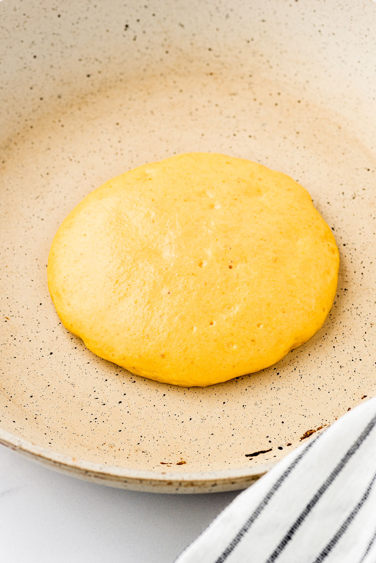 One pancake being cooked in a non-stick pan