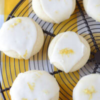 Seven Lemon Meltaway Cookies on a Black Cooling Rack on Top of a Plaid Yellow Tablecloth