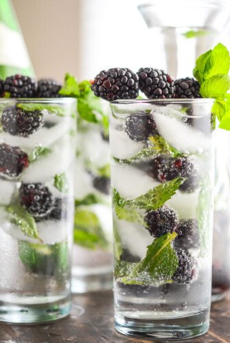 Glasses of Sparkling Blackberry Mint Aguas Frescas garnished with blackberries and mint sprigs.