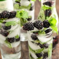 Glasses of Sparkling Blackberry Mint Aguas Frescas garnished with blackberries and mint sprigs.