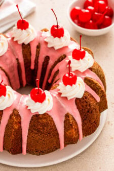 Whole cherry almond bundt cake with cherry glaze and maraschino cherries on top.