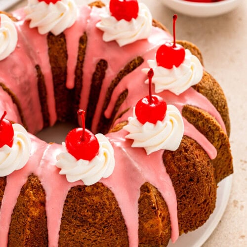 Whole cherry almond bundt cake with cherry glaze and maraschino cherries on top.