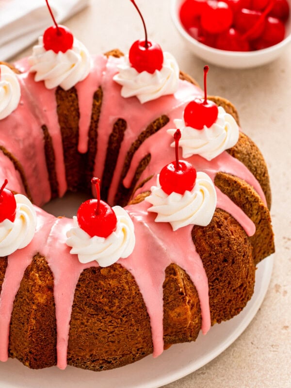 Whole cherry almond bundt cake with cherry glaze and maraschino cherries on top.