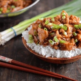 Crockpot Bourbon Chicken served over rice with chopsticks and scallions