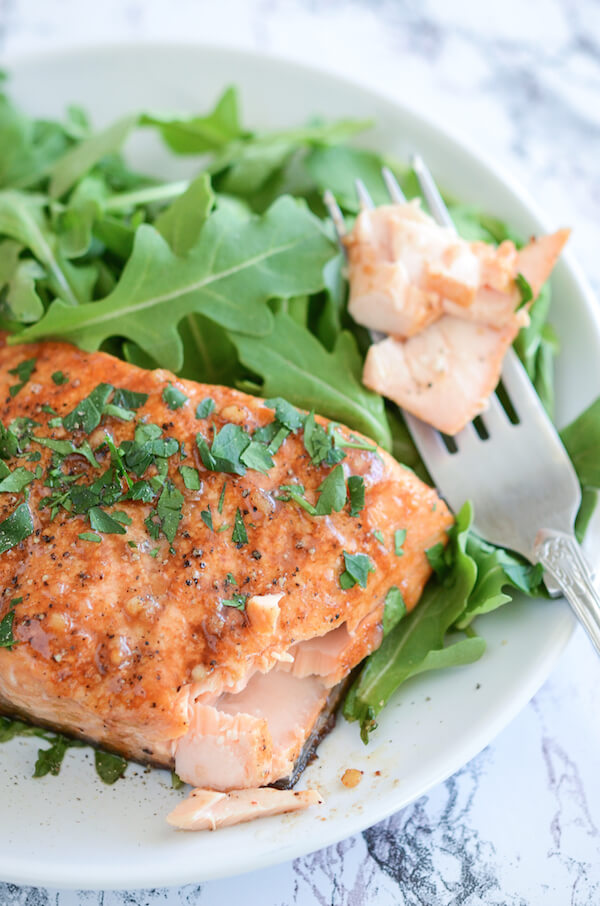 Balsamic Roasted Salmon on a white plate with piece of salmon on a fork