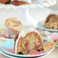 Slices of Honey Bun Cake with vanilla glaze on colorful plates with forks.