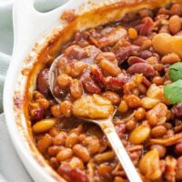 A spoonful of baked beans in a casserole dish.