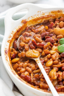 A spoonful of baked beans in a casserole dish.