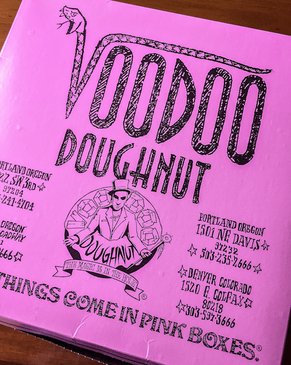 A Pink Box of Voodoo Doughnuts on a Wooden Table