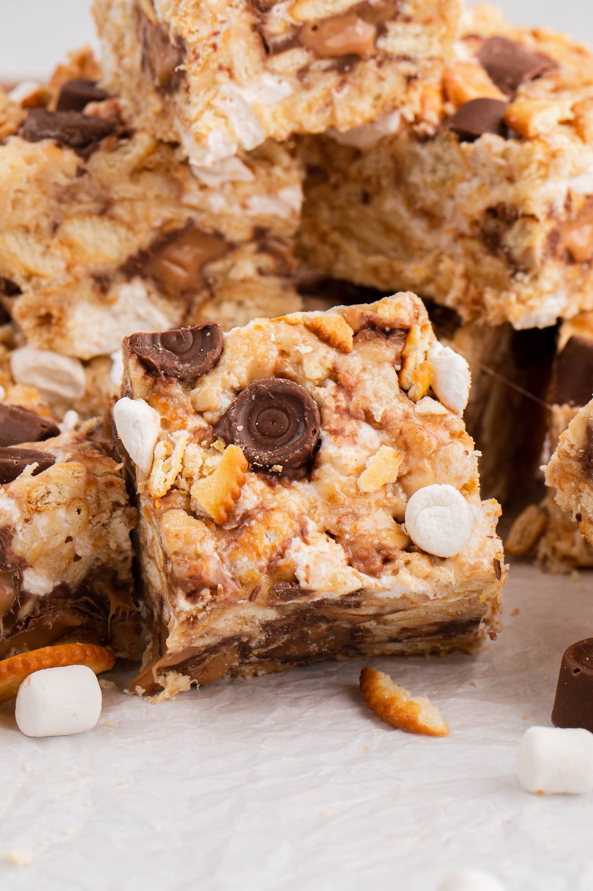 Cut marshmallow treat bars in a pile, with chocolate candies and marshmallows studded throughout.