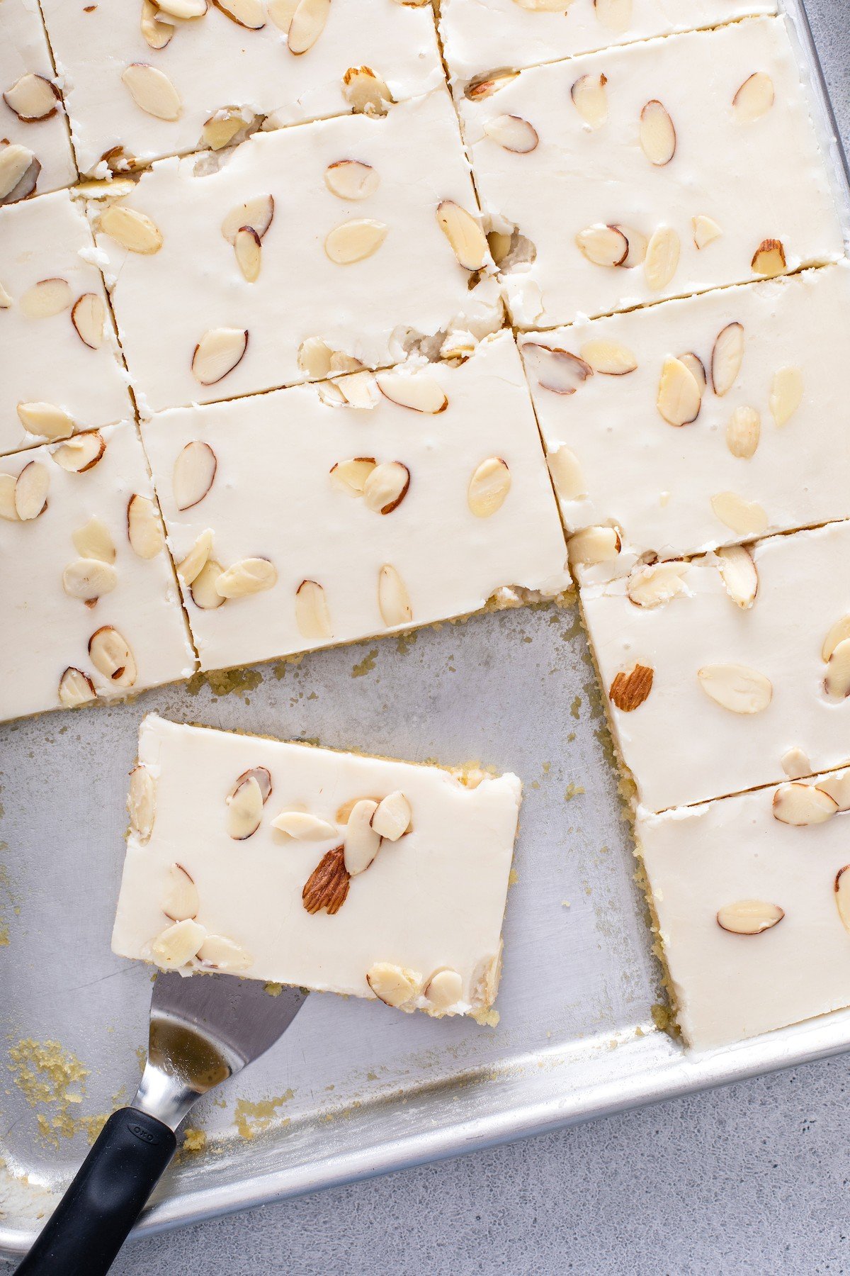 A slice of white Texas sheet cake with almonds.