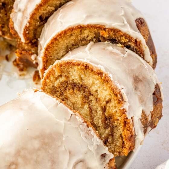 Sliced honey bun cake with glaze on a cake plate.