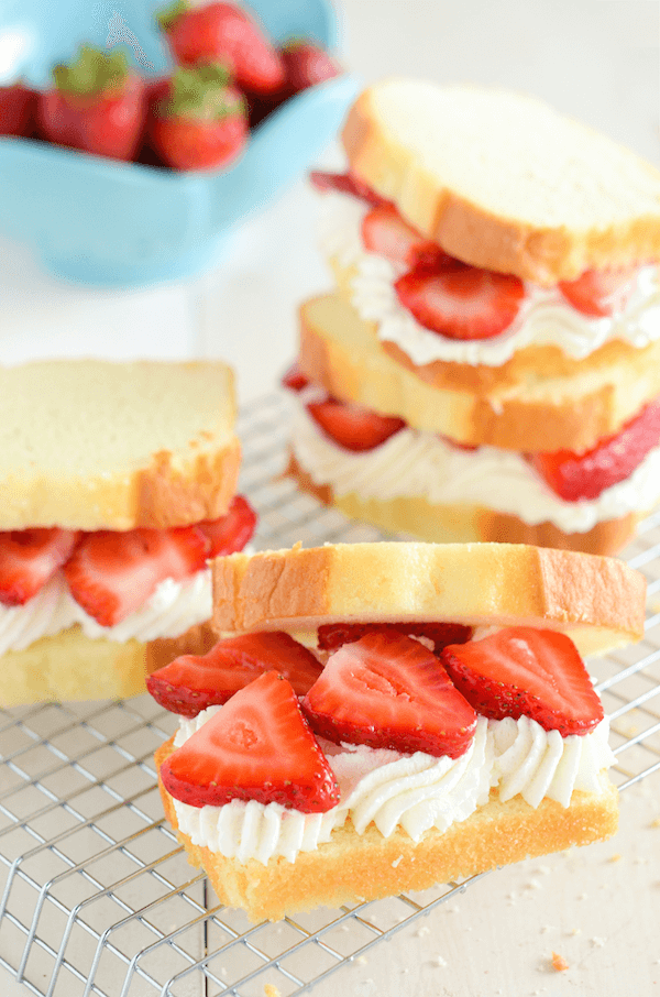 Strawberry Shortcake Sandwiches on a rack with sliced strawberries and whipped cream