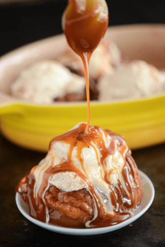 Baked Hasselback Apples topped with vanilla ice cream with Cinnamon Whipped Cream and drizzled Salted Caramel Sauce
