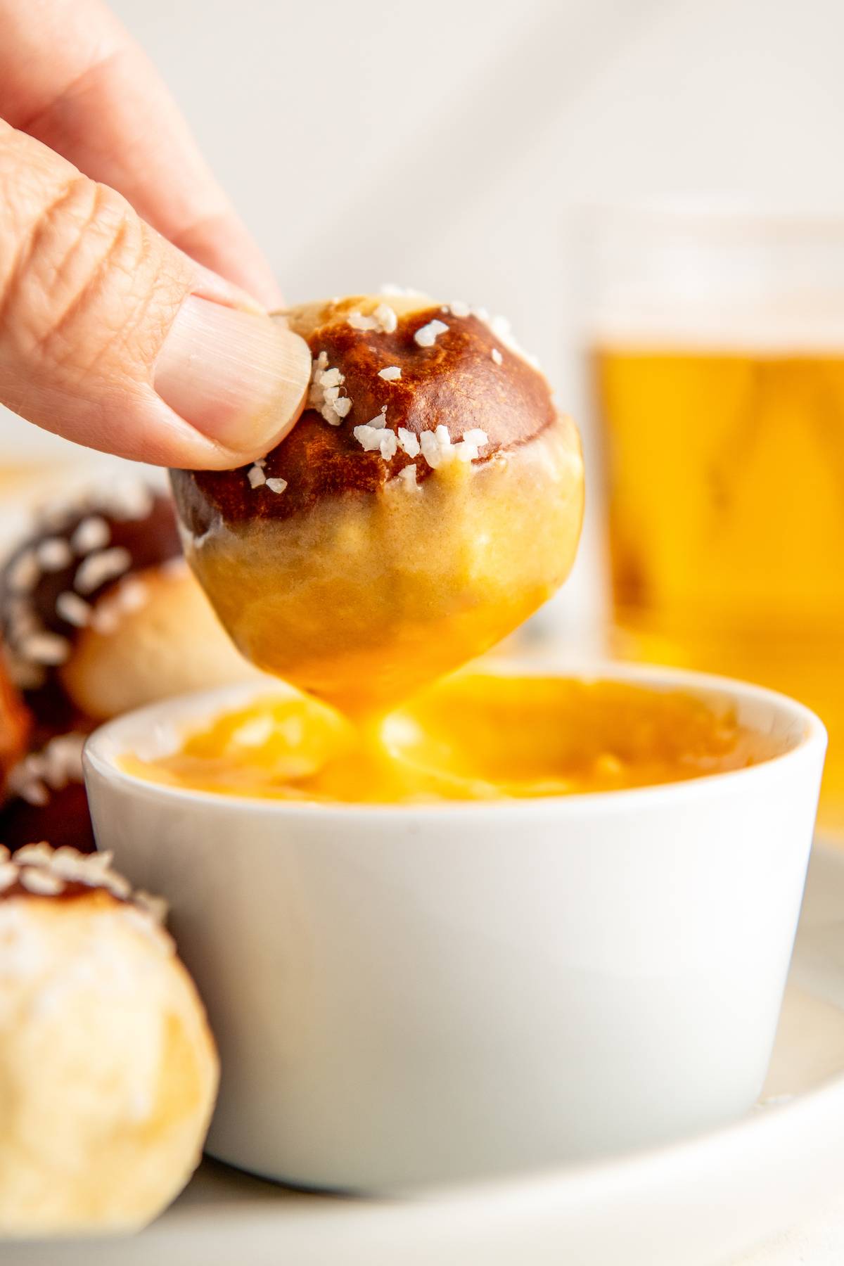Beer cheese dip in a bowl with a soft pretzel being dipped in the sauce.