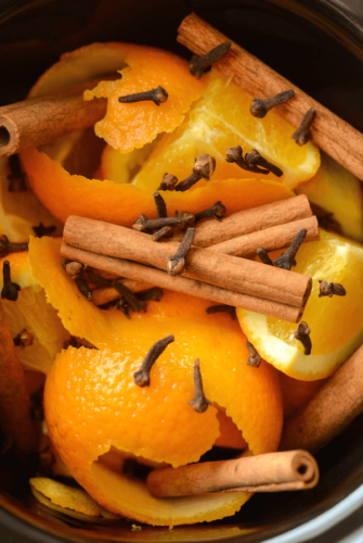 Cinnamon Orange Potpourri in a slow cooker crock with cloves, cinnamon sticks, and oranges