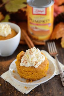 Pumpkin Mug cake set on a white plate topped with whipped cream and cinnamon