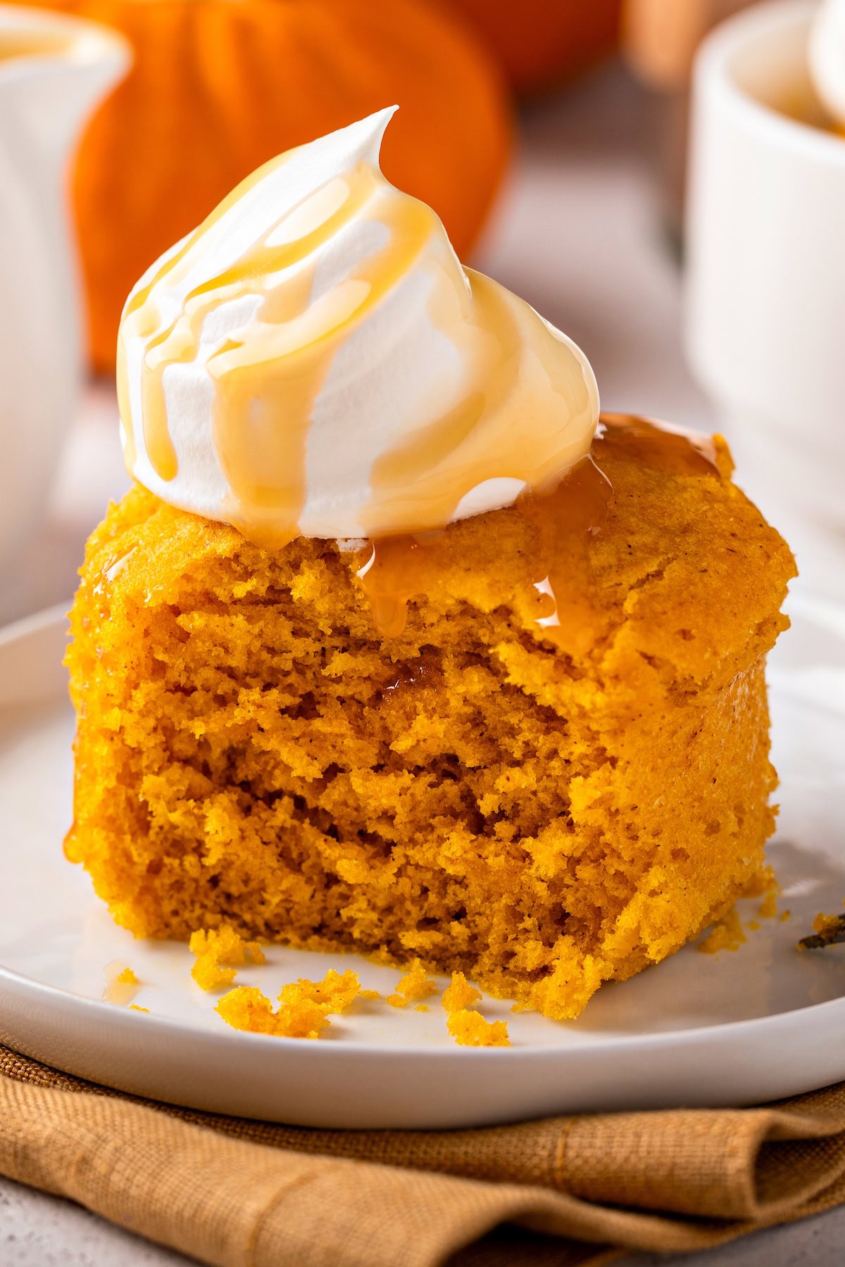 Fluffy pumpkin mug cake with airy whipped cream and salted caramel sauce.