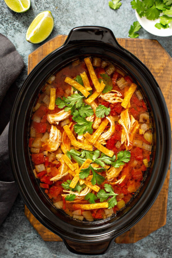 Chicken tortilla soup in a crockpot with tortilla strips on top.