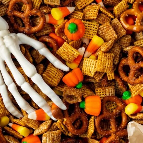 Plastic skeleton hand placed on a bowl of pumpkin chex.