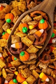 A large wooden serving spoon scooping Halloween chex mix.