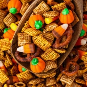 A large wooden serving spoon scooping Halloween chex mix.