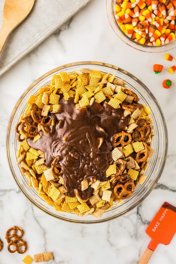 Melted sugar mixture poured over chex mix in a bowl.