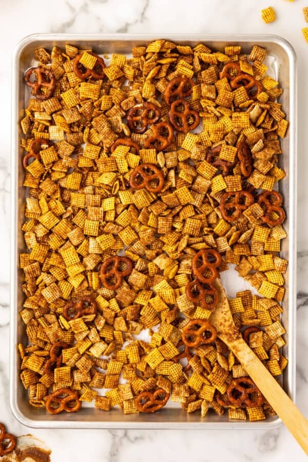 Pumpkin chex mix is spread in an even layer on a baking sheet.