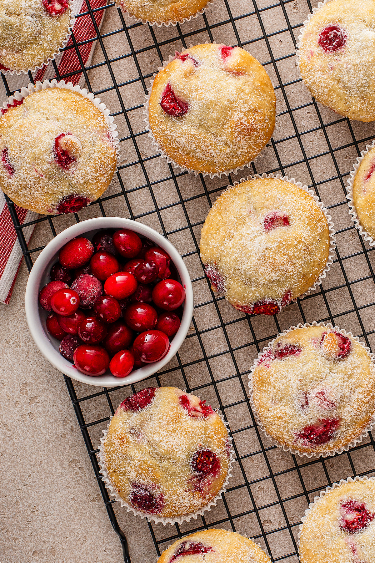 Cranberry muffins dipped in sugar on a cooling rack.