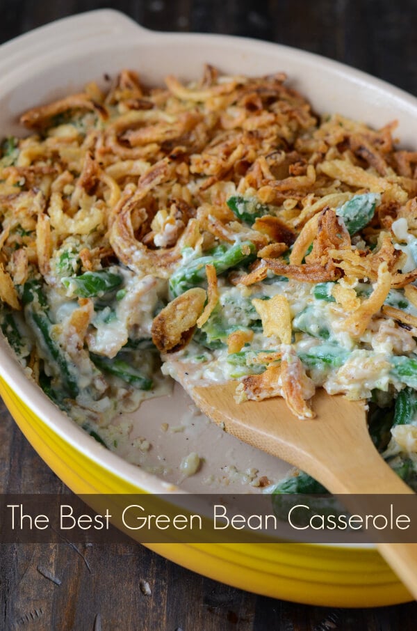 A Green Bean Casserole in a Yellow Dish with a Wooden Spoon